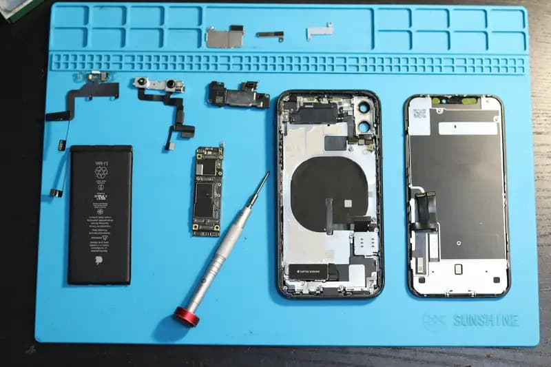 iPhone components disassembled on a blue repair mat